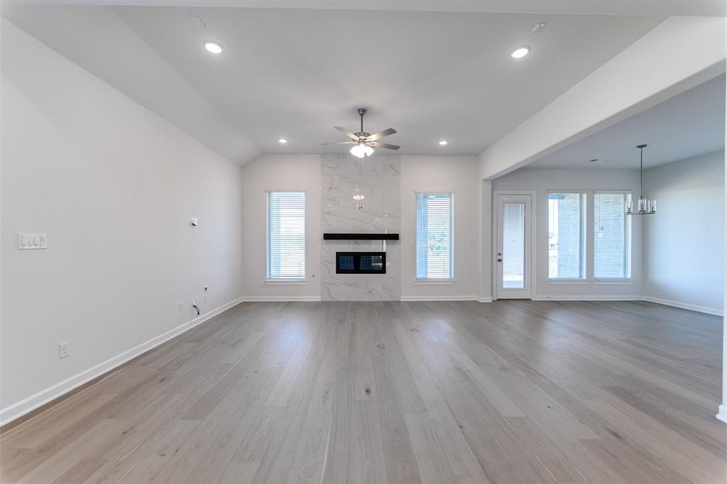 3908 Friendship Court Forney, TX 75126 - Photo 5 of 29 an empty room with wooden floor fireplace and windows