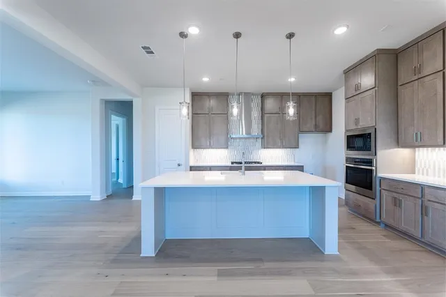 a large kitchen with kitchen island a sink stainless steel appliances and cabinets
