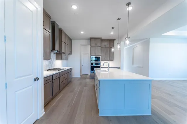 a large kitchen with stainless steel appliances kitchen island a large counter top and wooden floors