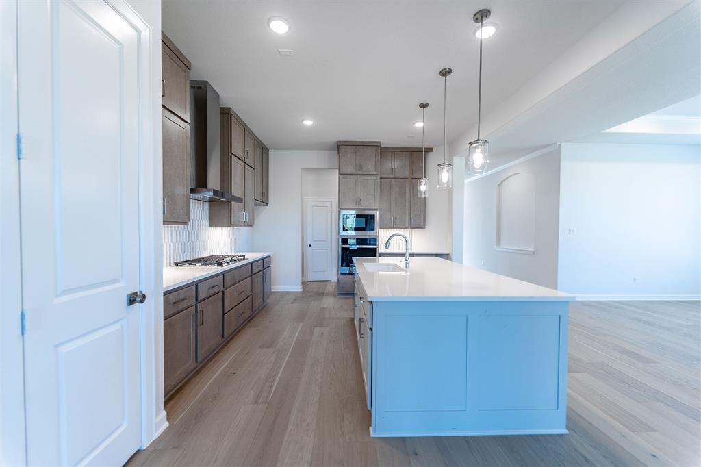 3908 Friendship Court Forney, TX 75126 - Photo 8 of 29 a large kitchen with stainless steel appliances kitchen island a large counter top and wooden floors