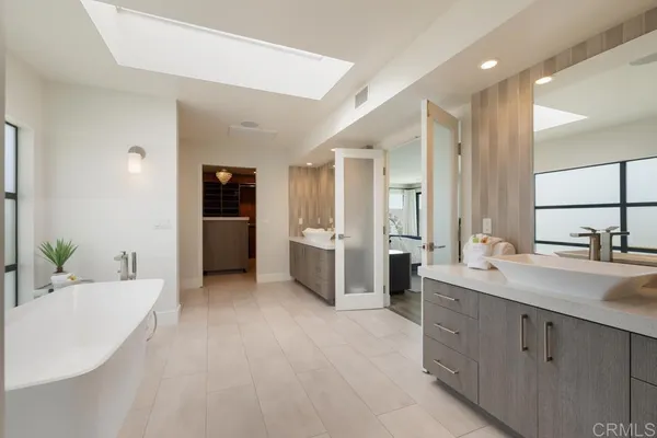 a spacious bathroom with a double vanity sink a large mirror and a bathtub