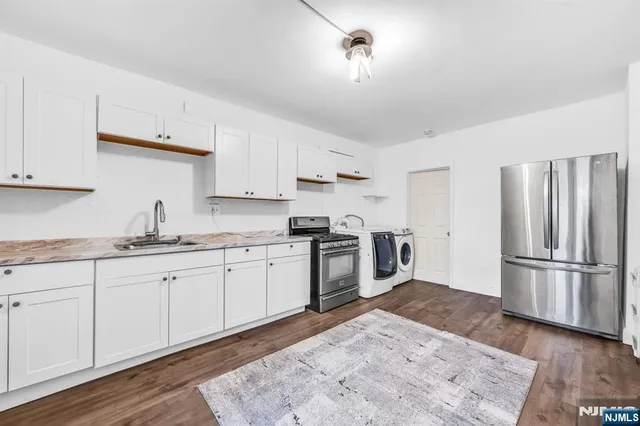 a kitchen with granite countertop a refrigerator stove top oven and sink