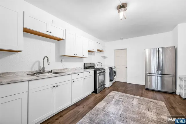 a kitchen with sink a refrigerator and white cabinets
