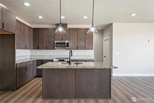 a kitchen with kitchen island granite countertop a sink a counter top space stainless steel appliances and cabinets