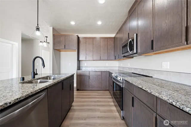 a kitchen with kitchen island granite countertop a sink stainless steel appliances and cabinets