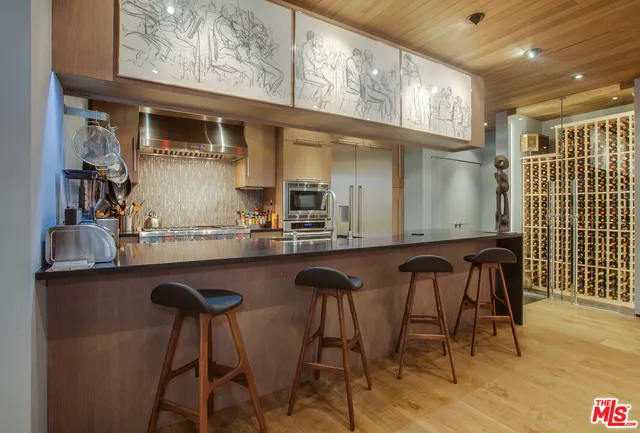 a kitchen with stainless steel appliances granite countertop a table chairs in it and wooden floors