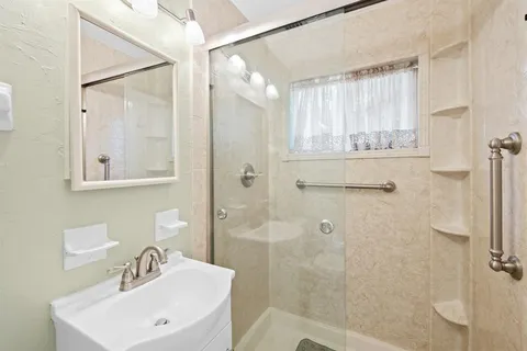 a bathroom with a sink a toilet a mirror and shower