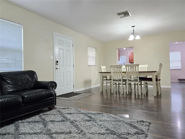 a living room with furniture and a dining table with wooden floor