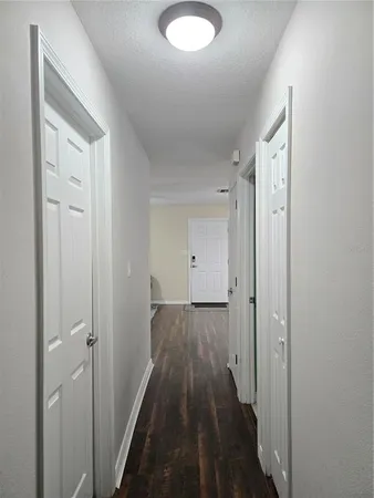 a view of a hallway with wooden floor and a bathroom