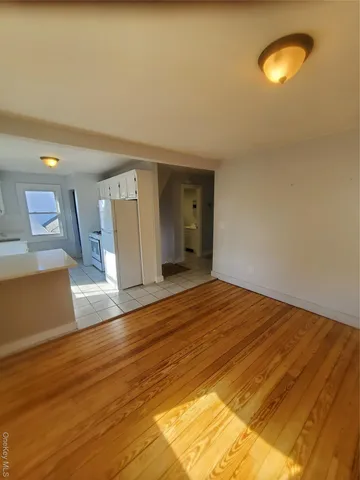 a view of kitchen and empty room with wooden floor