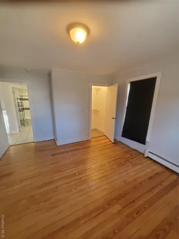 a view of an empty room with a window and wooden floor