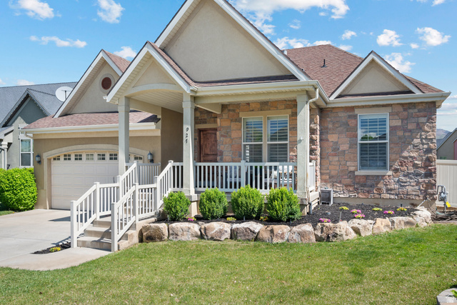 927 Iris Lane Mapleton, UT 84664 - Photo 31 of 31 Stone facade, covered front porch, white railing, attached garage, and landscaped front yard with decorative boulders