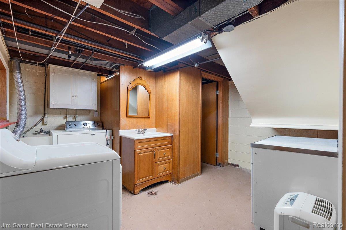 1010 Nottingham Road Grosse Pointe, MI 48230 - Photo 22 of 30 Utility space featuring a laundry area with a utility sink, a single-door wooden vanity with a white countertop and basin, and a wall-mounted mirror