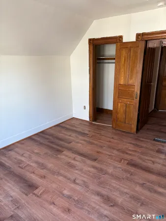 a view of an empty room with wooden floor and cabinet