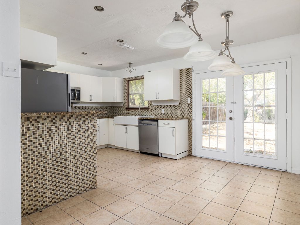 6206 Hogan Avenue Austin, TX 78741 - Photo 1 of 1 a kitchen with stainless steel appliances granite countertop a sink a stove a refrigerator a microwave oven with white cabinets