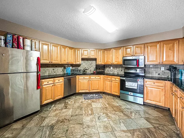 a kitchen with stainless steel appliances granite countertop a stove sink and window