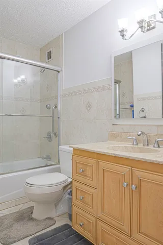 a bathroom with a granite countertop toilet a sink and a mirror