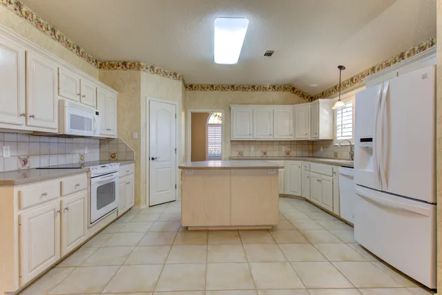 a kitchen with white cabinets and white appliances