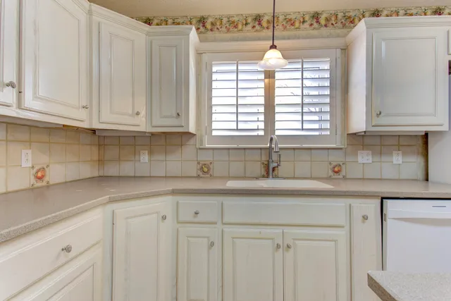 a kitchen with white cabinets and window