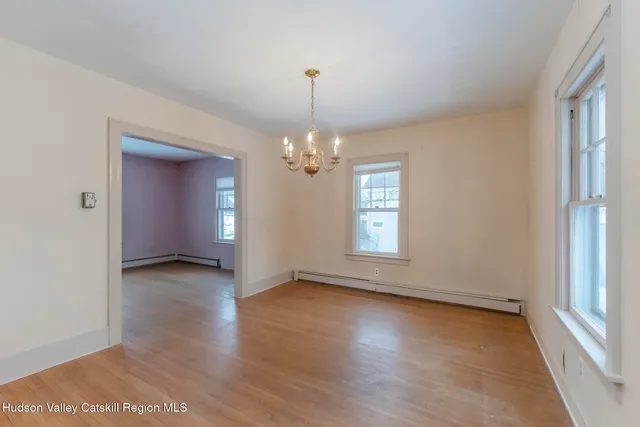 an empty room with wooden floor chandelier and windows