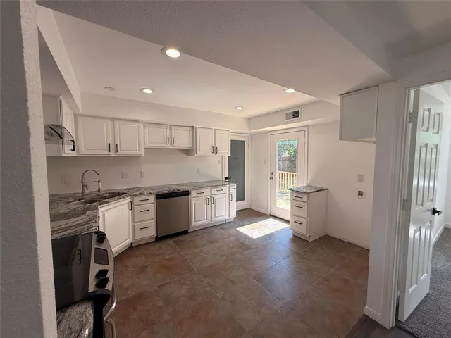 a large kitchen with stainless steel appliances granite countertop a stove a sink and a refrigerator