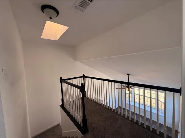 a view of staircase with railing and white walls