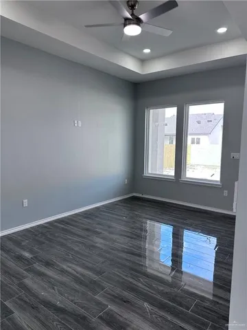 an empty room with wooden floor fan and windows