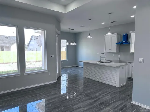 a view living room with stainless steel appliances granite countertop a sink a window and wooden floor