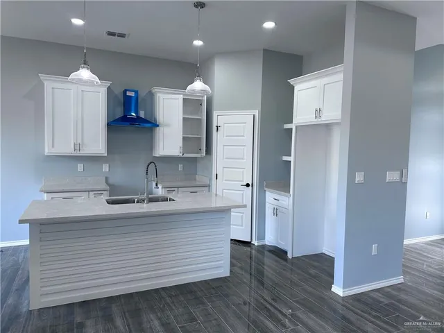 a kitchen with white cabinets and sink