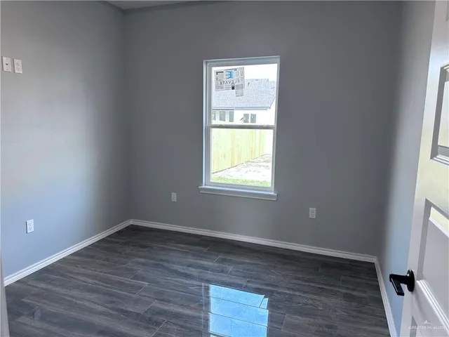an empty room with a window and wooden floor