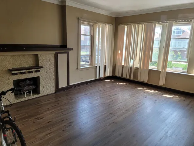 an empty room with wooden floor fireplace and windows