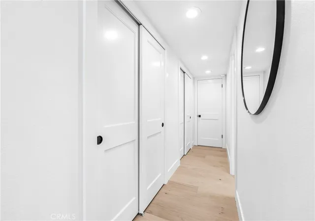 a view of a hallway with wooden floor and a large mirror