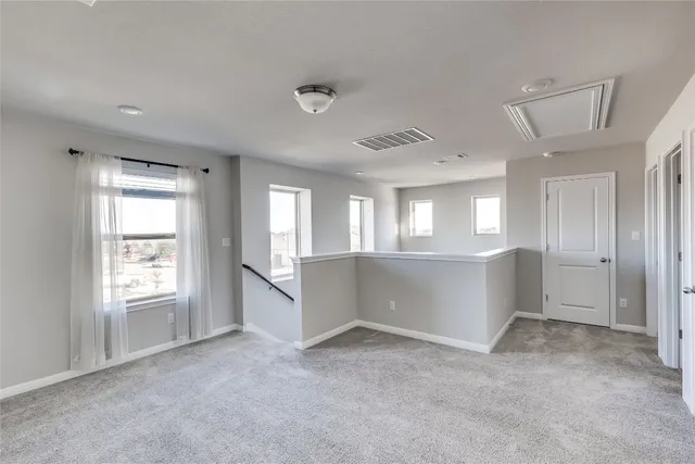 a view of an empty room with window and kitchen area