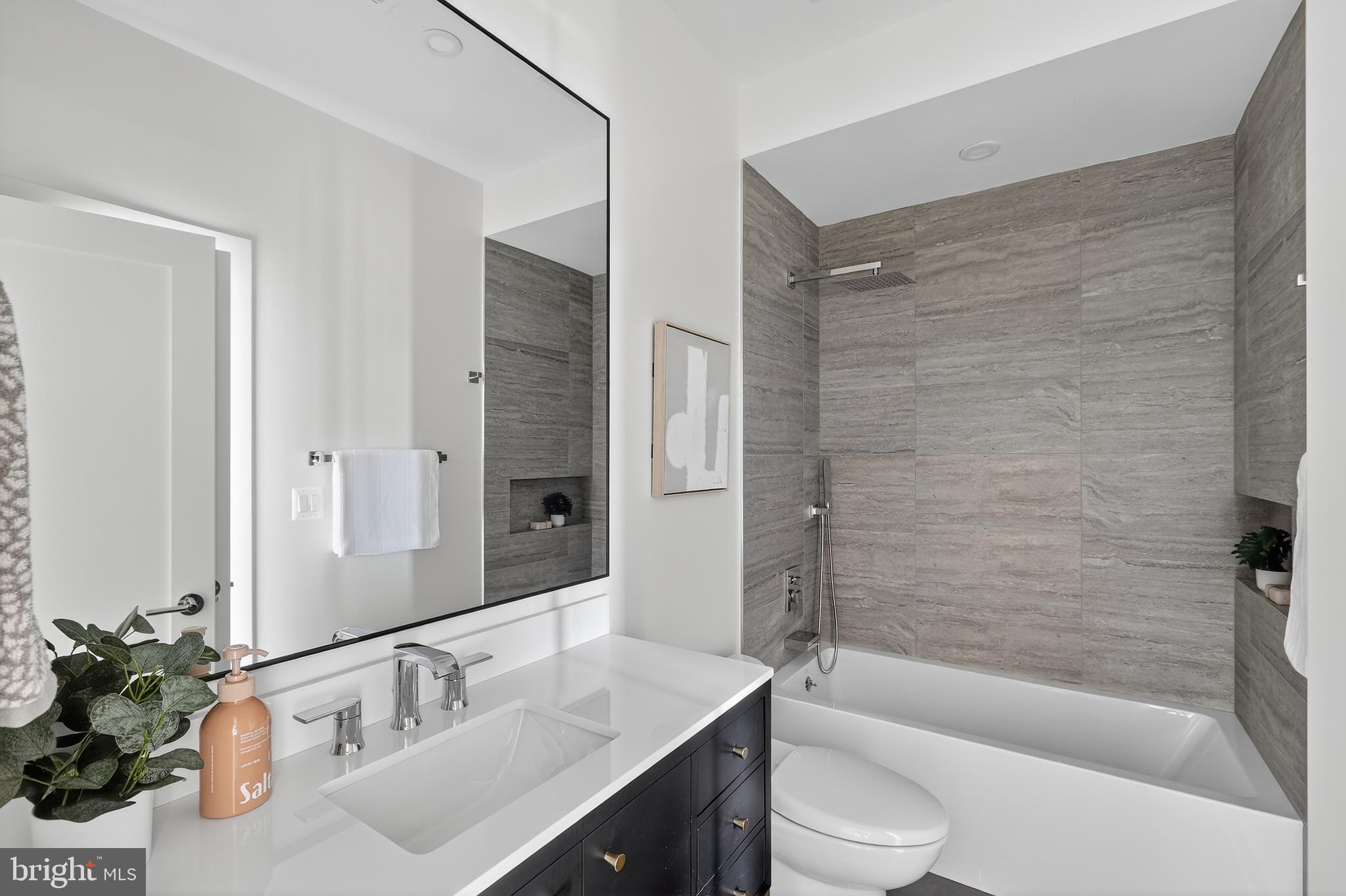 828 21st Street Northeast, Unit 2 Washington, DC 20002 - Photo 14 of 27 a bathroom with a bathtub shower sink mirror vanity and toilet