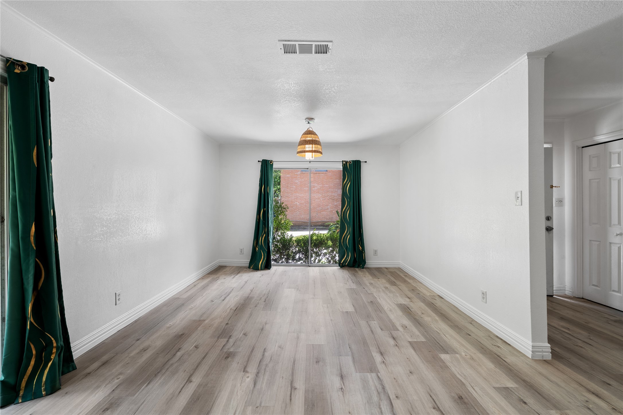 6303 Crab Orchard Road, Unit 3 Houston, TX 77057 - Photo 8 of 30 Adjacent to the main living area is this intimate dining space, defined by a stunning woven pendant light that adds a touch of organic warmth. The large sliding glass door offers a view of the brick architectural details outside, creating a high-end, urban-loft vibe for your dinner parties.