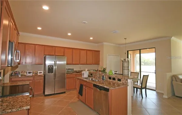 a kitchen with stainless steel appliances granite countertop a stove a refrigerator a sink a dining table and chairs with wooden floor