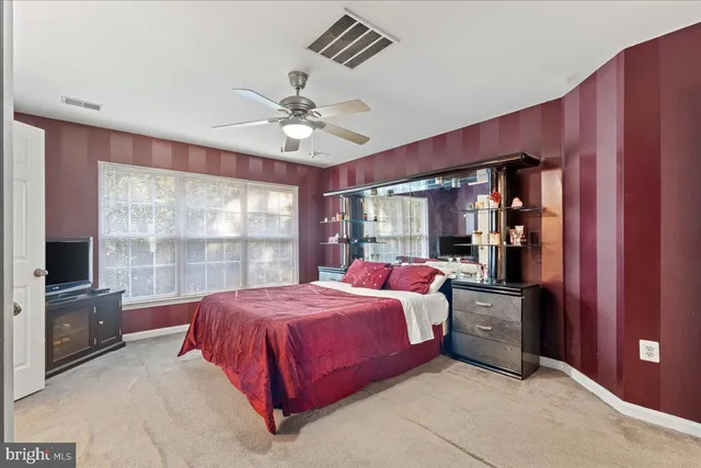 a bedroom with a bed dresser and a large window