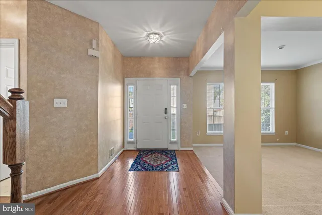 a view of a hallway with wooden floor and a bathroom
