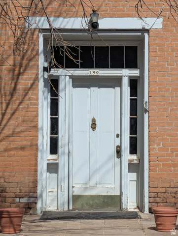 190 North 200 E Street Beaver, UT 84713 - Photo 2 of 40 Brick facade entry with a paneled white door, transom window, sidelights, and a wall-mounted light fixture