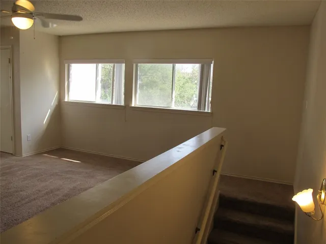 an empty room with windows and fan
