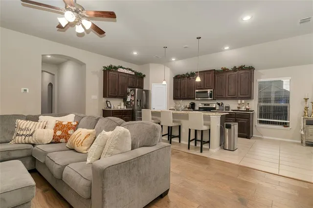 a living room with stainless steel appliances furniture and a kitchen view