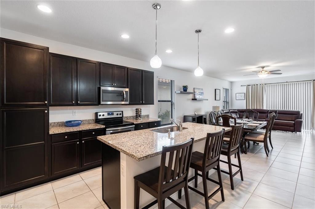 5586 Useppa Drive Ave Maria, FL 34142 - Photo 3 of 30 a kitchen with cabinets a sink stainless steel appliances and chairs