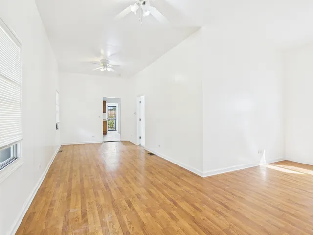 an empty room with wooden floor and ceiling fan