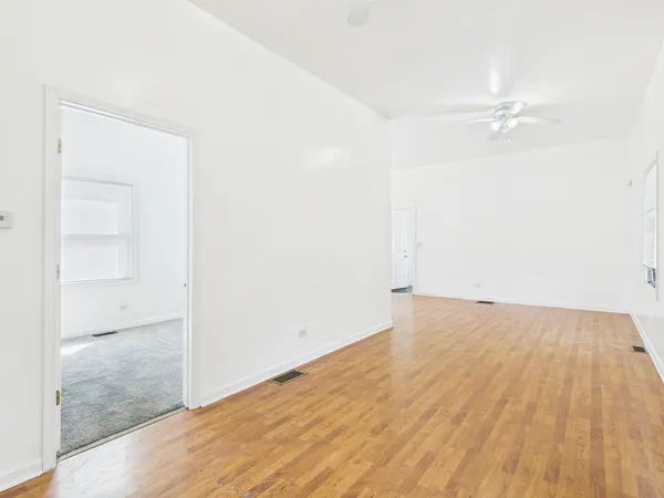 an empty room with wooden floor and fan