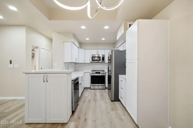 a kitchen with a refrigerator a oven and white cabinets with wooden floor