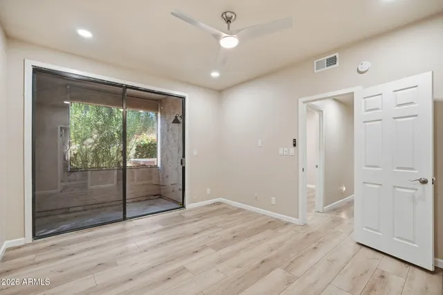 a view of empty room with wooden floor and fan