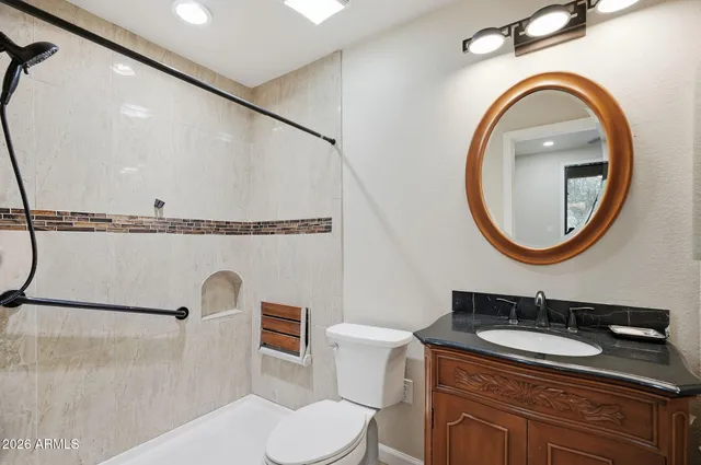 a bathroom with a granite countertop toilet sink and mirror