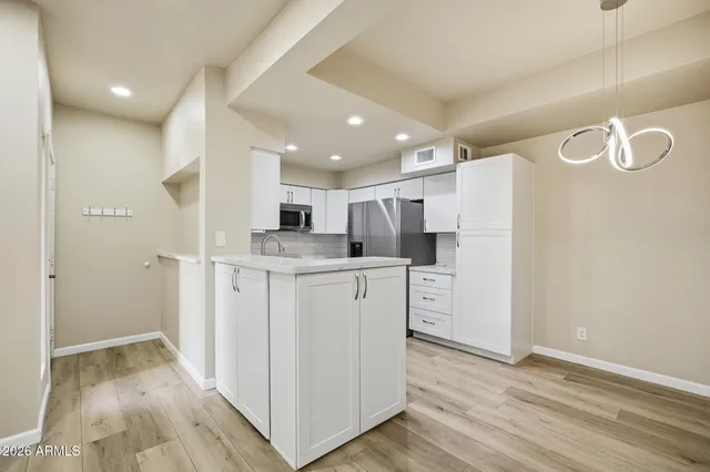 a kitchen with white cabinets and refrigerator