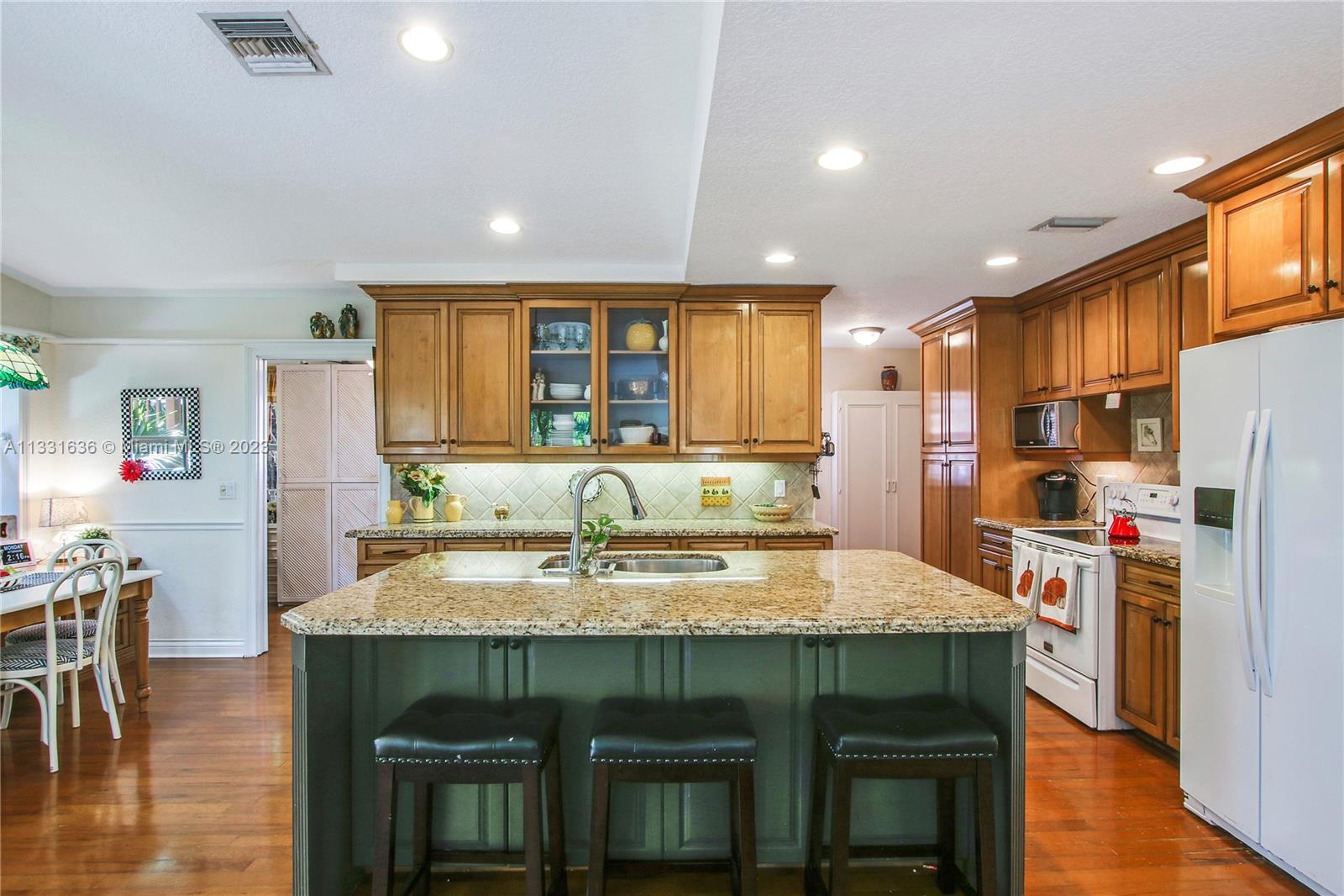361 Zenith Lane Juno Beach, FL 33408 - Photo 19 of 36 a kitchen with stainless steel appliances granite countertop a table chairs stove and refrigerator