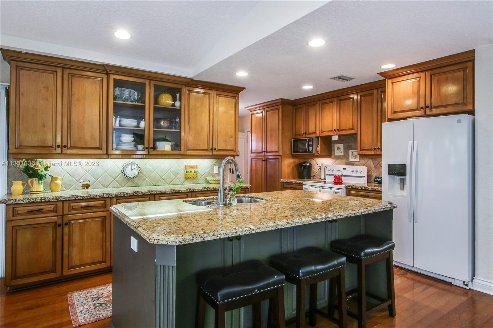 361 Zenith Lane Juno Beach, FL 33408 - Photo 20 of 36 a kitchen with a stove a sink a refrigerator and wooden cabinets